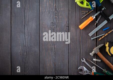 Arbeitswerkzeug des Assistenten. Maßband, Schraubendreher, Hammer, Schraubenschlüssel, Klemme, Schrauben, Bohrer und andere Werkzeuge auf einer Holzoberfläche. Stockfoto