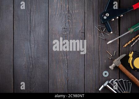 Arbeitswerkzeug des Assistenten. Maßband, Schraubendreher, Hammer, Schraubenschlüssel, Klemme, Schrauben, Bohrer und andere Werkzeuge auf einer Holzoberfläche. Stockfoto