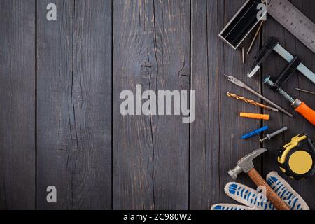 Arbeitswerkzeug des Assistenten. Maßband, Schraubendreher, Hammer, Schraubenschlüssel, Klemme, Schrauben, Bohrer und andere Werkzeuge auf einer Holzoberfläche. Stockfoto