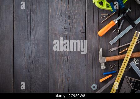 Arbeitswerkzeug des Assistenten. Maßband, Schraubendreher, Hammer, Schraubenschlüssel, Klemme, Schrauben, Bohrer und andere Werkzeuge auf einer Holzoberfläche. Stockfoto