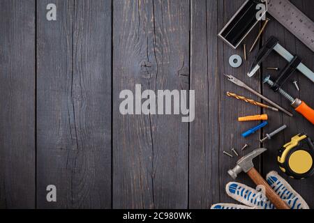 Arbeitswerkzeug des Assistenten. Maßband, Schraubendreher, Hammer, Schraubenschlüssel, Klemme, Schrauben, Bohrer und andere Werkzeuge auf einer Holzoberfläche. Stockfoto