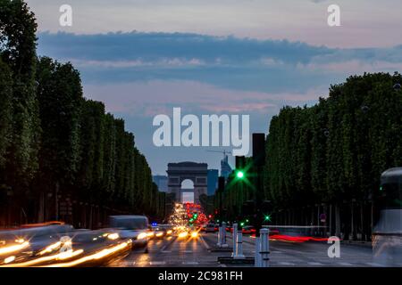 Eine Langzeitbelichtung bei schwachem Licht der berühmten Champs-Elysees Avenue in Paris mit dem ikonischen Arch im Hintergrund. Bäume werden als Silhouetten auf gesehen Stockfoto