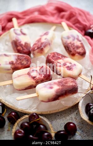 Frische Sahne und Kirsche hausgemachten Eis auf weiße Keramikplatte mit Früchten und Textil platziert Stockfoto