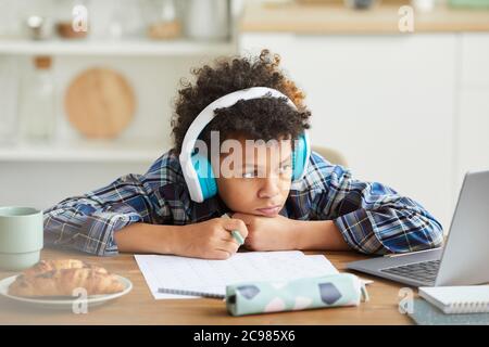 Afrikanischer Schuljunge in Kopfhörer sitzen am Tisch und beobachten Online-Unterricht auf Laptop er online studieren Stockfoto