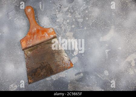 Schmutziger und rostiger Spatel auf Zementgrund Stockfoto