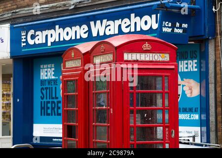 Ursprüngliche alte rote Telefonzellen, die von BT betrieben werden, stehen vor einem Ladengeschäft für Autotelefone, das gerade aufgrund der Entwicklung in der Telefonkommunikationsbranche geschlossen wurde. Bournemouth England (120) Stockfoto