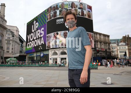 BBC Radio 1 DJ Greg James im Piccadilly Circus, London, als die Radio 1 'Up Yours Corona' Kampagne auf dem Piccadilly Lights Bildschirm angezeigt wird. Das 10-minütige Display zeigt eine Person aus jedem Land der Welt. Stockfoto