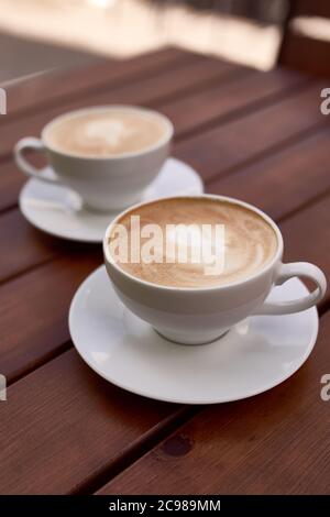 Zwei Tassen Cappuccino auf dem Holzhintergrund Stockfoto