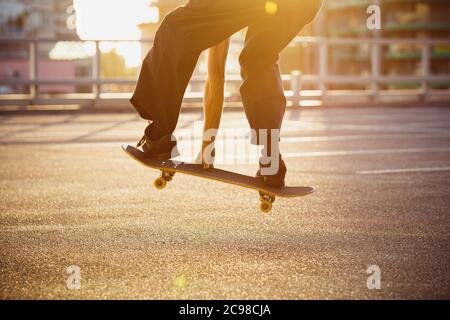 Skateboarder macht einen Trick auf der Straße der Stadt, Nahaufnahmen. Junger Mann in Turnschuhen und Cap Reiten und Skateboarding auf dem Asphalt. Konzept von Freizeitaktivitäten, Sport, Extremsport, Hobby und Bewegung. Stockfoto