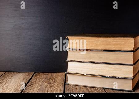 Bücher auf einem Holztisch im rustikalen Stil auf dem Hintergrund eine Schultafel gestapelt. Das Konzept der willkommen zurück in der Schule. Copy space Stockfoto