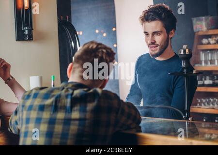 Besucher teilt Geheimnisse mit einem Barkeeper. Nahaufnahme Rückansicht Schuss. Mann fragen Rat an einen Kellner. Gespräch, freundliches Gespräch Stockfoto