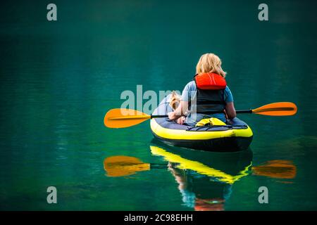 Kaukasische Frau Kajak mit ihrem australischen Silky Terrier Hund während des Sommers Nachmittag. Landschaftlich Schöner Turquoise Lake. Stockfoto