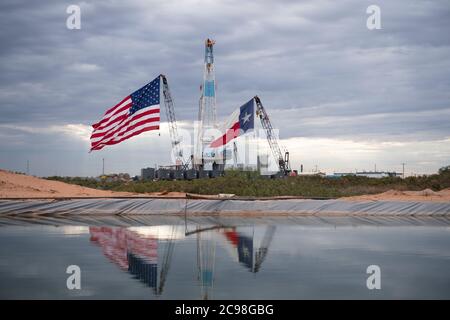 Midland, Texas, USA. Juli 2020. Die Flaggen Texas und USA zieren ein Bohrgerät südöstlich von Midland, TX, wo US-Präsident Donald Trump (nicht abgebildet) am 29. Juli 2020 nach einem Fundraisierer und Roundtable im benachbarten Odessa zu Besuch sein wird. Trump wird voraussichtlich Proklamationen unterzeichnen, die eine verstärkte Abhängigkeit von der Ölproduktion im Permian-Becken befürworten.Kredit: Bob Daemmrich/ZUMA Wire/Alamy Live News Stockfoto