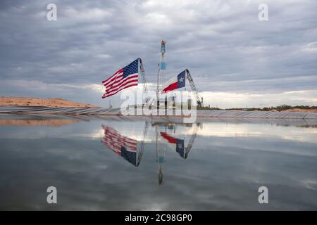 Midland, Texas, USA. Juli 2020. Die Flaggen Texas und USA zieren ein Bohrgerät südöstlich von Midland, TX, wo US-Präsident Donald Trump (nicht abgebildet) am 29. Juli 2020 nach einem Fundraisierer und Roundtable im benachbarten Odessa zu Besuch sein wird. Trump wird voraussichtlich Proklamationen unterzeichnen, die eine verstärkte Abhängigkeit von der Ölproduktion im Permian-Becken befürworten.Kredit: Bob Daemmrich/ZUMA Wire/Alamy Live News Stockfoto