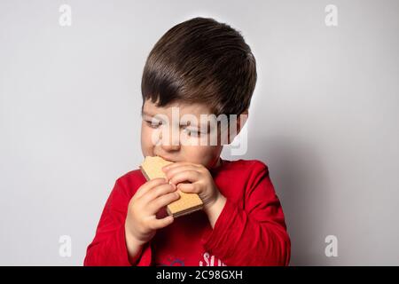 Kleiner Junge isst gerne eine knusprige Waffel. Glückliches Baby und lecker. Stockfoto