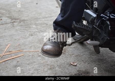 Setzen Sie sich auf Ihr Motorrad und starten Sie den Motor mit Fuß Startstange oder Kick Starter, Lass uns gehen. Stockfoto