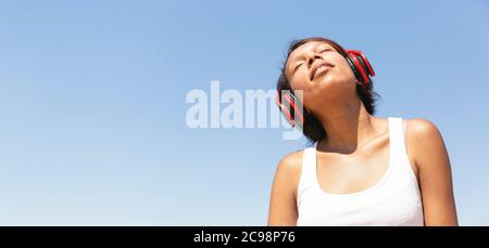 Porträt einer jungen Brünette Frau, die Musik über ihre Kopfhörer hört. Leerzeichen für Text. Lifestyle-Konzept. Stockfoto