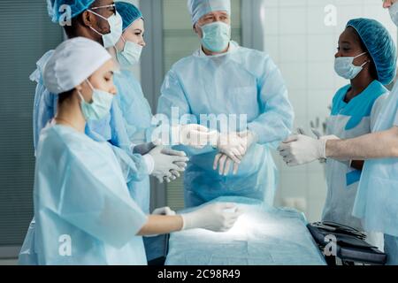 Team von Ärzten anziehen Handschuhe, Vorbereitung für schwierige Operation, Nahaufnahme Stockfoto