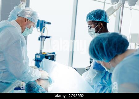 Oberarzt, der während der Operation die Oxygern-Maske an einen Patienten aufsetzt. Stockfoto