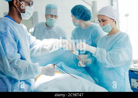 Schöne Krankenschwester geben Schere afro Arzt in einer Brille. Close up Seite sehen Foto Stockfoto