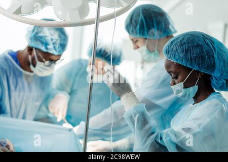 Junge ehrfürchtige weibliche Anästhesist setzt die Dropper im Krankenhauszimmer. Close up Seitenansicht Foto Stockfoto