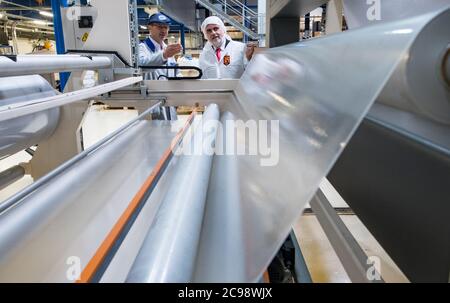 29. Juli 2020, Sachsen-Anhalt, Bitterfeld-Wolfen: Thomas Olszowy (l.), Prokurist des Folienwerks Wolfen, und Armin Willingmann (SPD), Wirtschaftsminister von Sachsen-Anhalt, sprechen auf einer Extrusionsanlage zur Herstellung von EVA-Folien für Sicherheitsglas. Das Folienwerk Wolfen beschäftigt 140 Mitarbeiter und produziert Folien auf derzeit sieben Extrusionsanlagen mit einer maximalen Kapazität von 20,000 Tonnen. Das Unternehmen erwirtschaftet einen Umsatz von rund 35 Millionen Euro, rund 70 Prozent der Produktion werden exportiert. Im Rahmen der Sommertournee des Ministers vergibt das Wirtschaftsministerium Sachsen-Anhalt Preise an 'fut Stockfoto