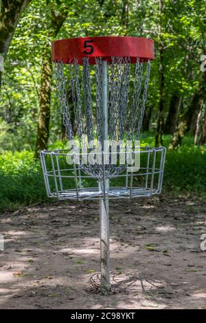 Ein roter #5 Disc Golfkorb leer in den Wäldern auf einem Platz im Park im Schatten an einem sonnigen Tag in der Sommerzeit Nahaufnahme Stockfoto