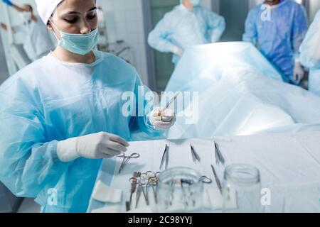 Schöne weibliche Arzt mit Schere und Pinzette. Nahaufnahme Foto. Copy space. Krankenschwester hält Schere hinter dem Tisch Stockfoto