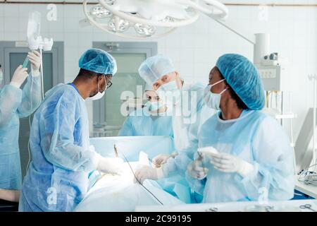 Konzentriertes Operationsteam, das mit einem Patienten in einem Operationssaal arbeitet gut ausgebildeter Anästhesist begleitet den Patienten während der Operation. Stockfoto