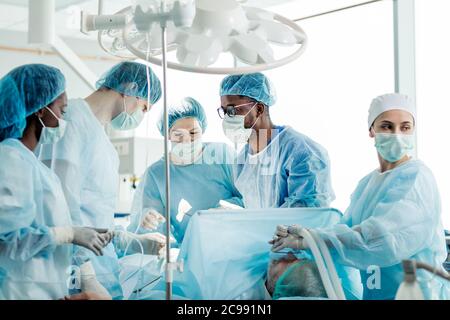 Professionelle ehrfürchtige Team von Chirurgen behandeln Verletzungen, und Fehlbildungen durch die Durchführung von Operationen am Patienten. Stockfoto