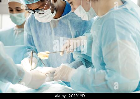 Team von Ärzten und Krankenschwestern desinfizieren die Wunde im Operationssaal. Nahaufnahme beschnittenes Foto Stockfoto