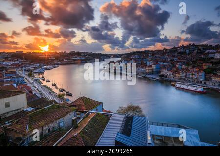 Sonnenuntergang über den Dächern der Stadt Porto. Fluss Douro in der portugiesischen Küstenstadt. Wolken und Sonnenstrahlen am Abend. Blick auf die Stadt vom Hügel Stockfoto