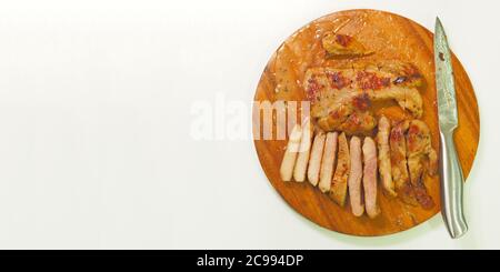 Schweinesteak mit einem Edelstahlmesser auf dem Schneidebrett platziert - weißer Hintergrund. Stockfoto