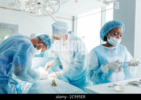 Multirassische Ärzte mit der Operation im Operationssaal Stockfoto