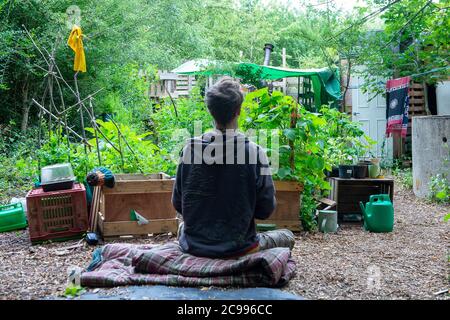 Wendover, Buckinghamshire, Großbritannien. Juli 2020. Ein Umweltaktivistin meditiert in ihrem Wendover Active Resistance Camp. Umweltaktivisten setzen ihren Kampf gegen die Zerstörung von Bäumen in Wendover fort. Die Arbeiten an Phase 1 der 134-Meilen-Hochgeschwindigkeitsstrecke von London nach Birmingham haben nun begonnen. Die äußerst umstrittene Eisenbahnlinie stellt 693 lokale Wildtierstätten und 108 alte Waldgebiete auf dem Weg der neuen Eisenbahn in Gefahr. Quelle: Maureen McLean/Alamy Stockfoto