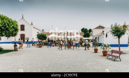Hauptplatz mit Menschen entspannen in Cafés in pictureque Porto Covo in Portugal Stockfoto