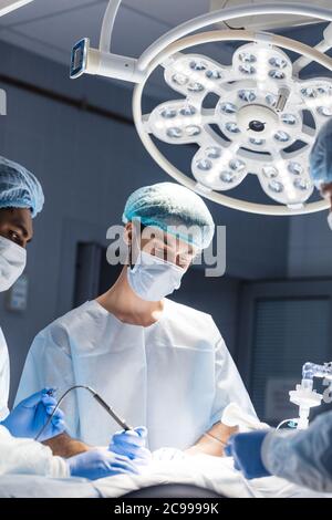Portrait von leitenden Arzt mit medizinischen Schutzmaske und scrub Cap. Reifen Chirurg in sterilen OP-Betrieb tragen, helle Zimmer. Stockfoto