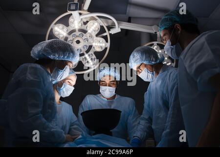 Low-Winkel-Ansicht des Teams von professionellen Chirurgen, die im Krankenhaus chirurgische Verfahren im Operationssaal. Krankenhaus, Medizin, Menschen Stockfoto