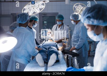Zwei jungen asiatischen und Kaukasische weiblichen Assistenten Vorbereitung chirurgische Instrumente und Werkzeuge auf eine Tabelle für eine Operation angeordnet, mit allen notwendigen eq Stockfoto