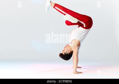 Asian Bboy stehend in frostigen Stunt Kopf nach unten Balancing in Luft mit Beinen - Street Artist Breakdance drinnen isoliert im Studio über weißen Backgrou Stockfoto