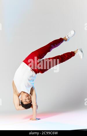 Handstand der koreanischen Breakdancer, die Breakdance Freeze auf den Kopf stellen und rote Hosen tragen. Vertikales Bild mit Copyspace, im Studio, auf weißem Hintergrund Stockfoto