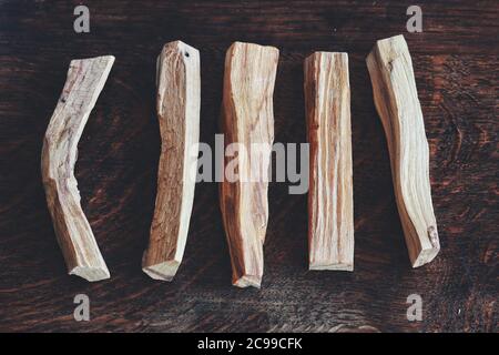 Flaches Lay von Palo Santo Sticks von Bursera graveolens (heiliges Holz) Baum auf dunkelbraunem Holztisch gelegt. 5 fünf Stäbchen in einer Reihe verteilen Stockfoto