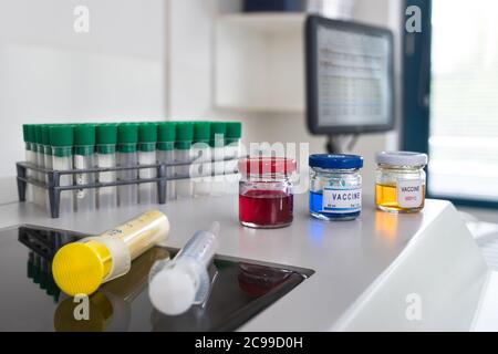 Coronavirus-Impfstoffforschung im wissenschaftlichen Labor mit medizinischer Software auf Computerbildschirm. Glasfläschchen mit roter, blauer oder gelber Flüssigkeit oder Spritzen. Stockfoto