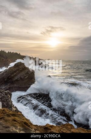 Krachende Wellen und dramatischer Himmel an der felsigen Pazifikküste, im Shore Acres State Park, in der Nähe von Charleston Oregon Stockfoto