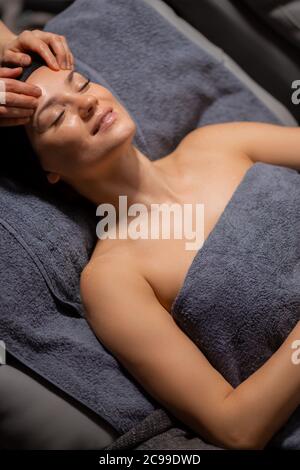 Junge und schöne Frau liegen auf Massage-Schreibtisch, entspannen und genießen, erhalten gesunde Behandlung der Haut, in Luxus-Wellness-Center Stockfoto