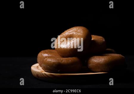 Holzbrett mit Donuts auf schwarzem Hintergrund Stockfoto