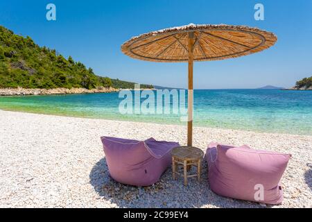 Liegestühle und Sonnenschirm am Leftos Gialos Strand, Alonnisos, Griechenland Stockfoto