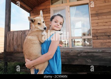 Portrait von kleinen hübschen Mädchen in Kleid hält ihren Hund auf den Händen und Blick auf die Kamera im Freien Stockfoto