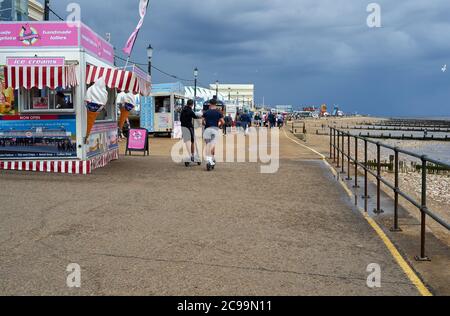 Hunstanton, Norfolk, England, Großbritannien - 25. Juli 2020: Menschen, die an einem bewölkten Sommertag am Strand spazieren. Stockfoto