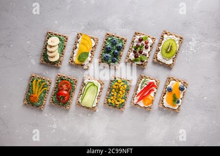 Set von hausgemachten Sandwiches mit Gemüse, Obst, Beeren, Chlorella, Spirulina und Käse. Kiwi, Traube, Banane, Heidelbeere, Pfirsich, Mandarine, Pfeffer Stockfoto